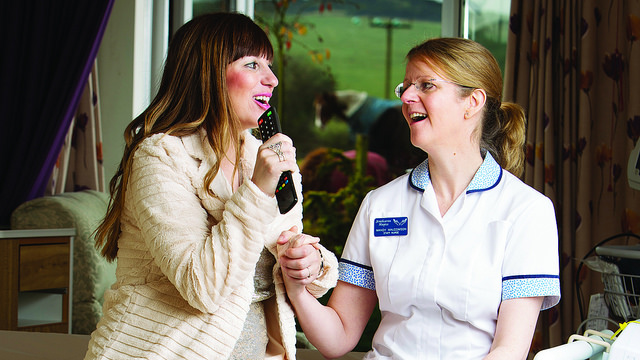 A photo of two women singing in a hospice center.