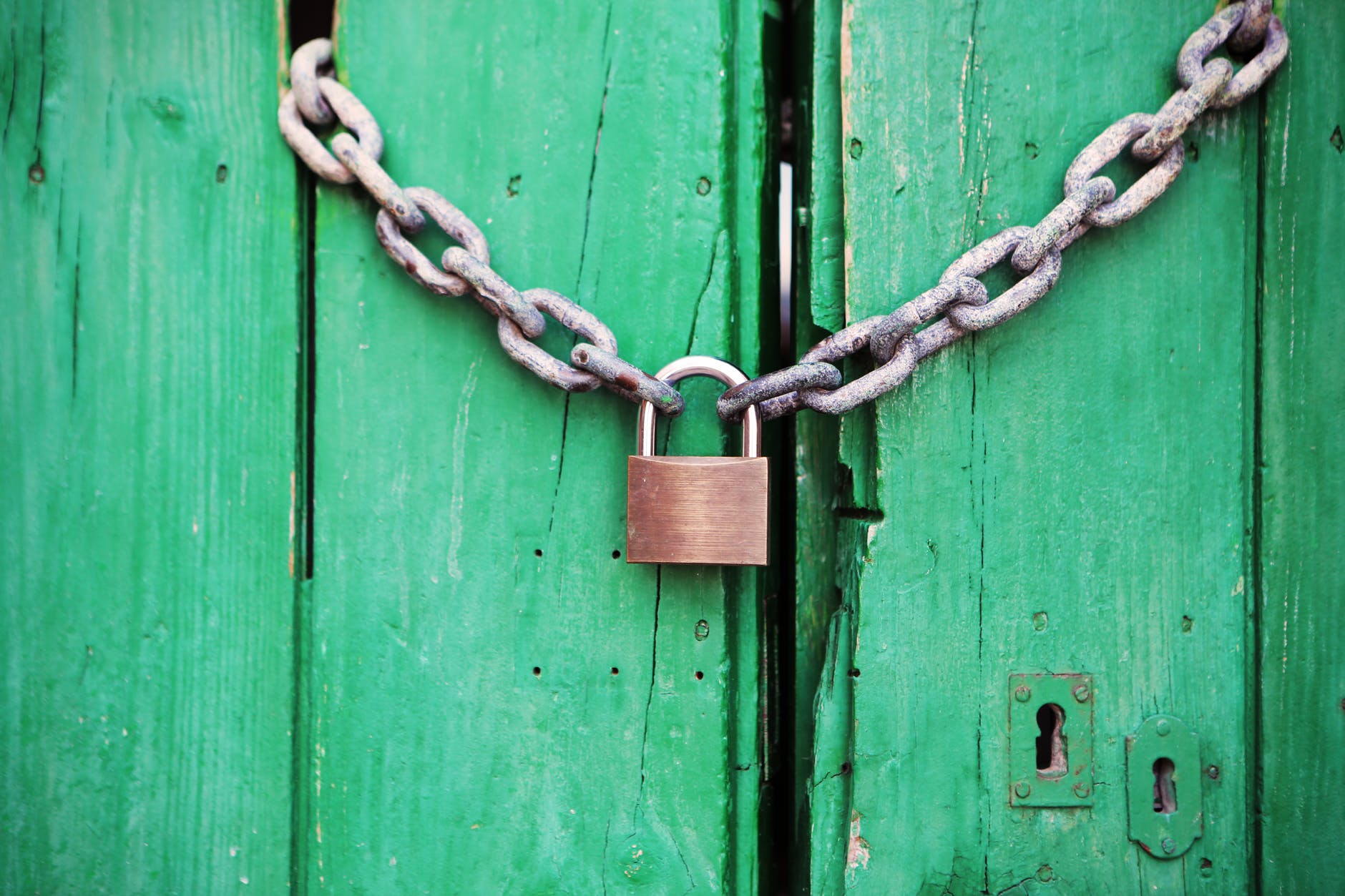 Green closed doors secured with a chair and padlock