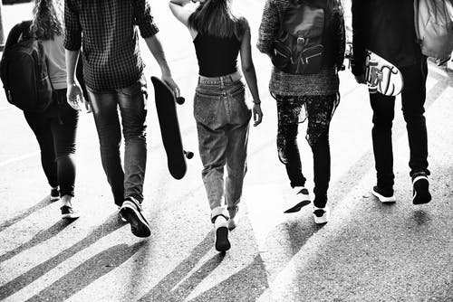 Black and white photo from behind of five young people walking 
