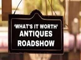 Black hanging sign which reads What's it worth? Antiques Roadshow 