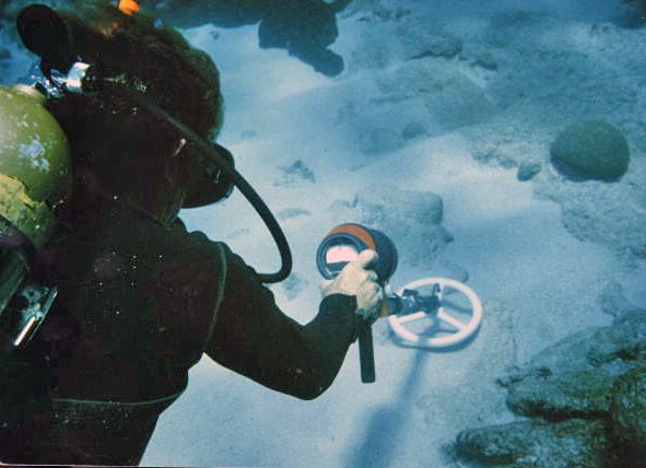 Scuba diver with a metal detector underwater
