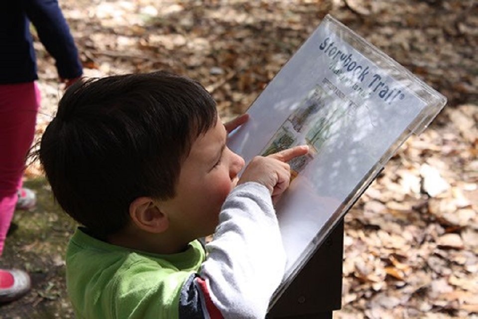 A child excitedly reading a story trail board.