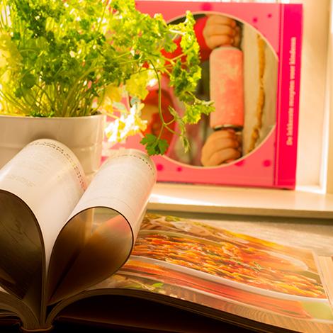 Open book with pages folded in the shape of a heart, a plant and rolling pin