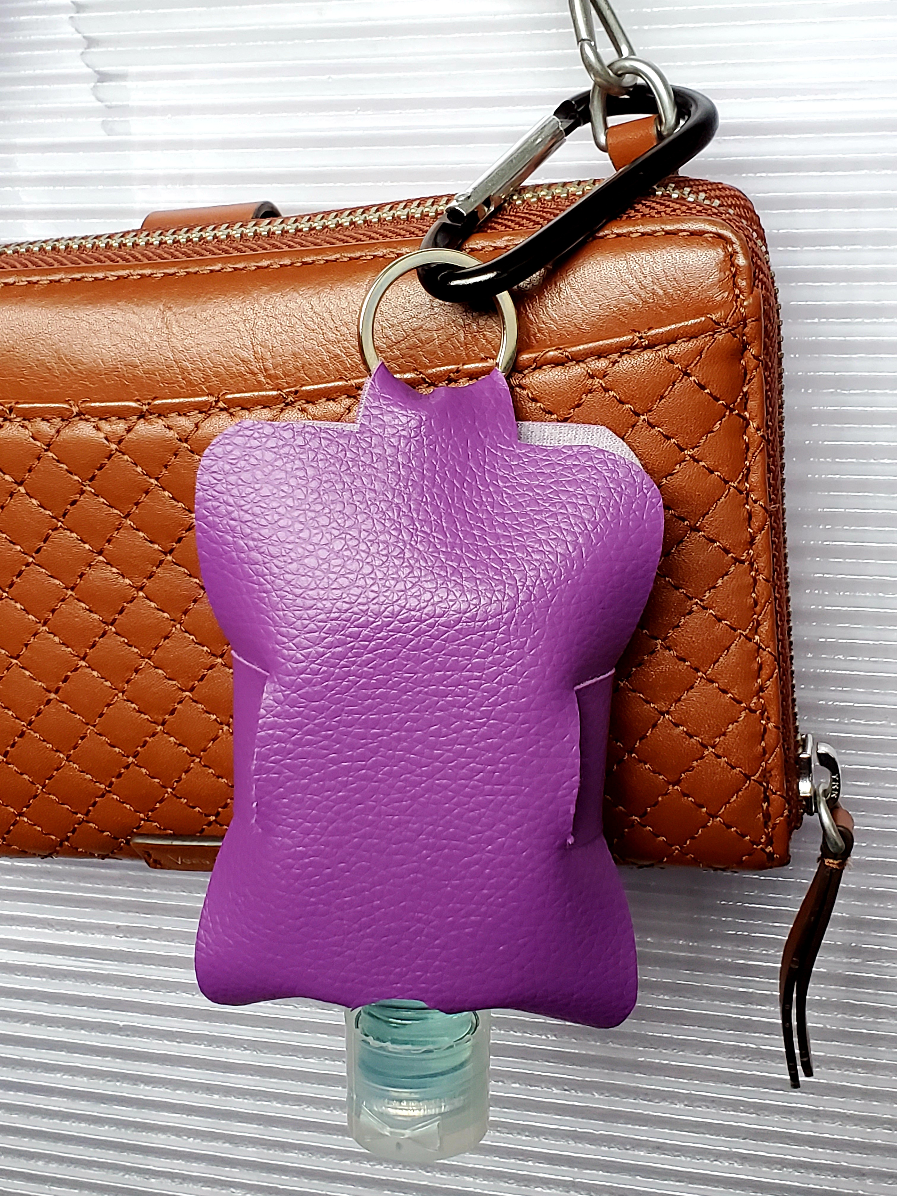 hand sanitizer pouch hanging off of a purse. 