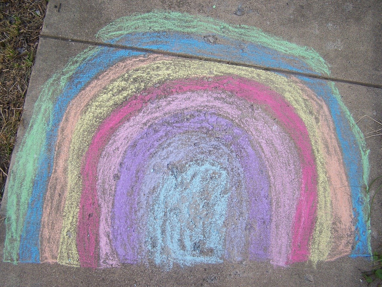 Rainbow chalk art on a sidewalk.