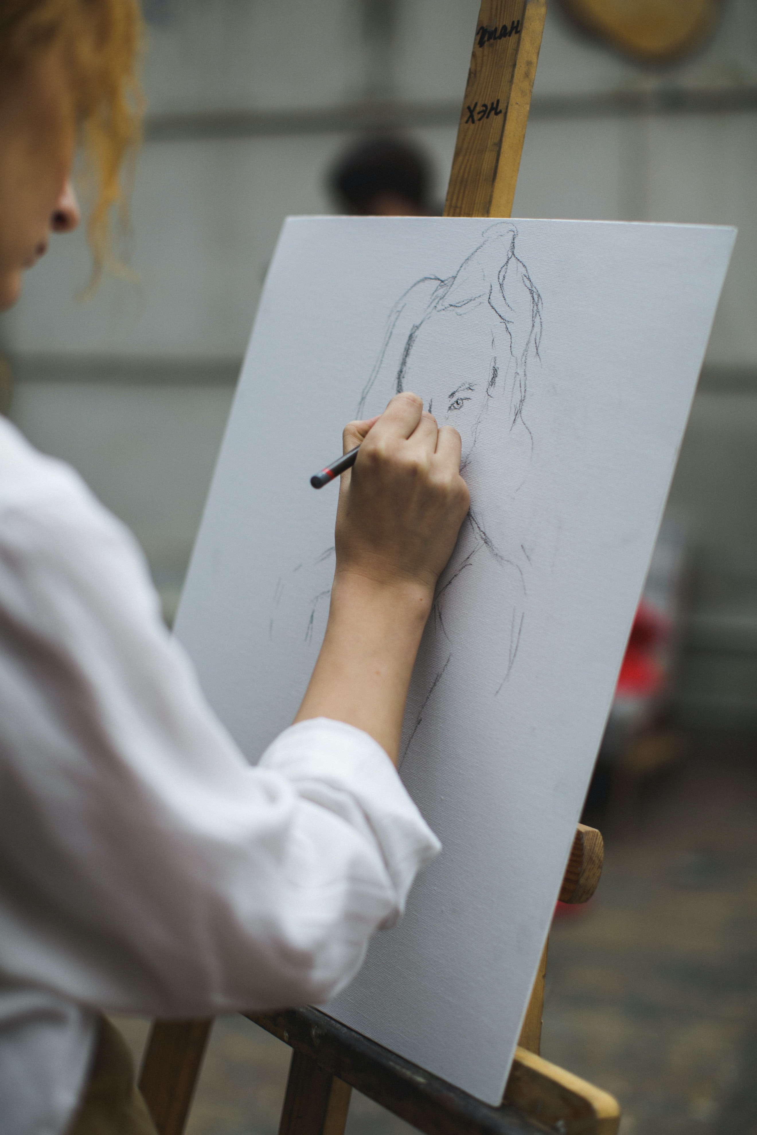 a woman sketches a figure on paper