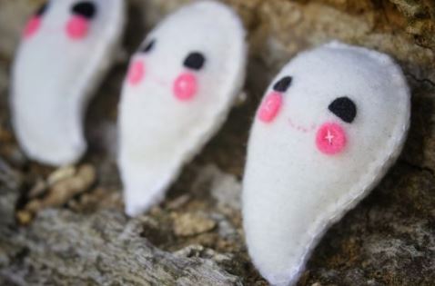 little ghosts made out of felt sit on a table in a row