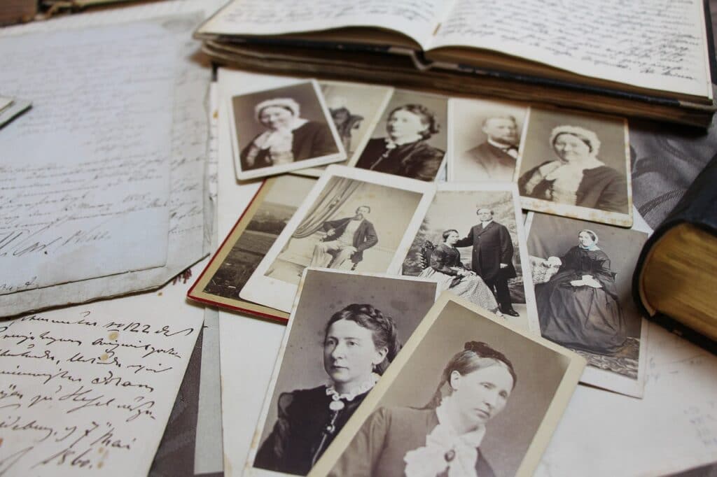 Old black and white photos scattered on top of an open book and hand-written journal pages.