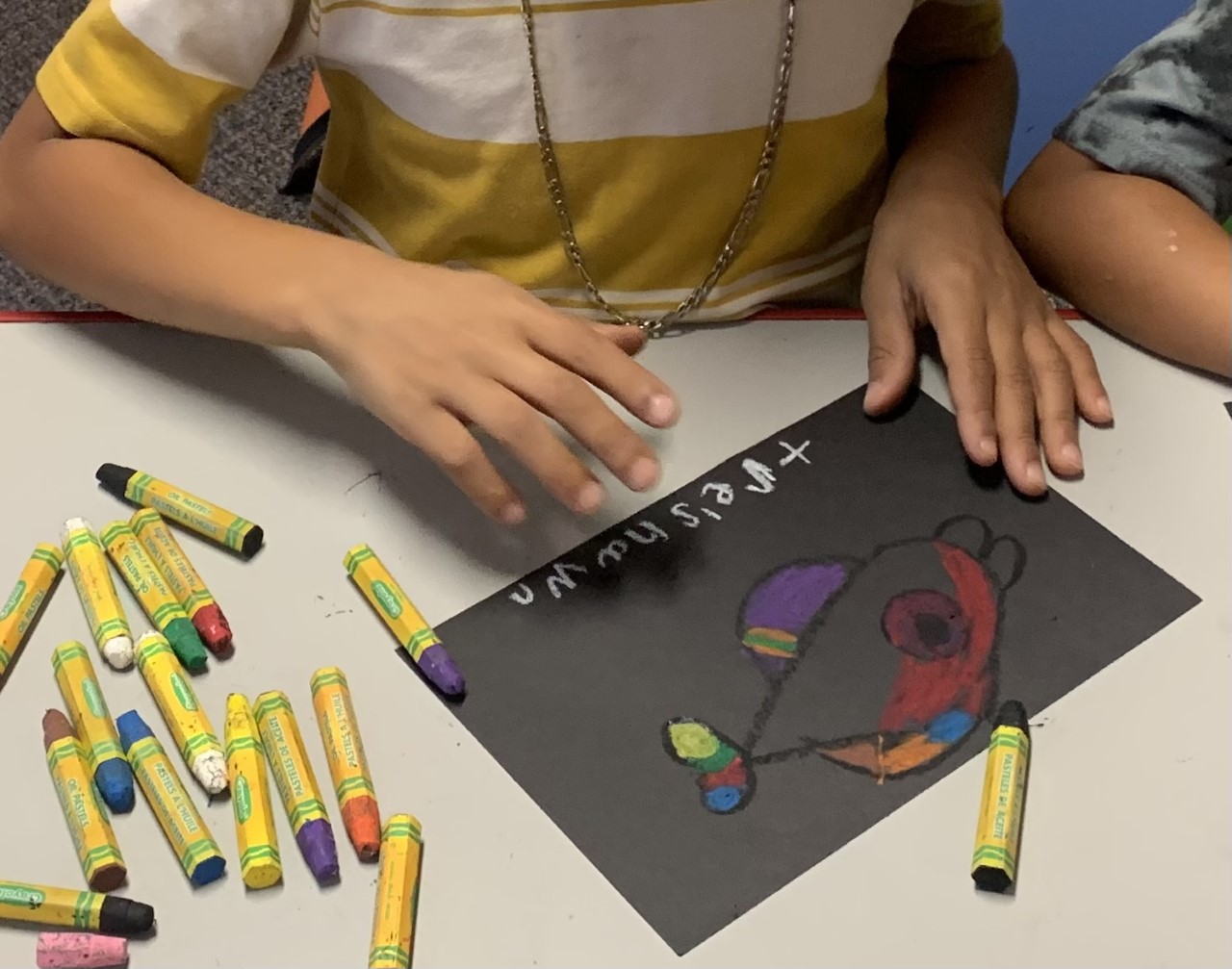 Child drawing fish with oil pastel