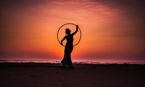 silhouette of a woman holding hula hoop on beach 