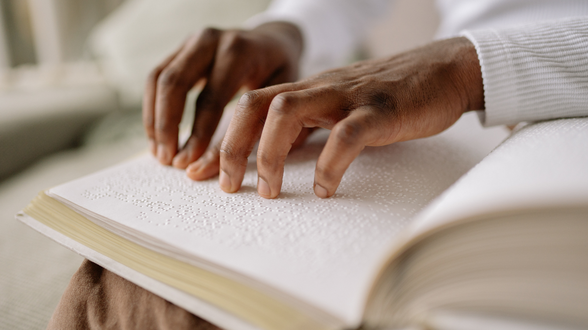 Man's hands reading a braille book.