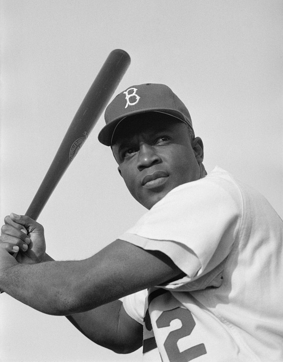 A black and white photo of Jackie Robinson holding a baseball bat.