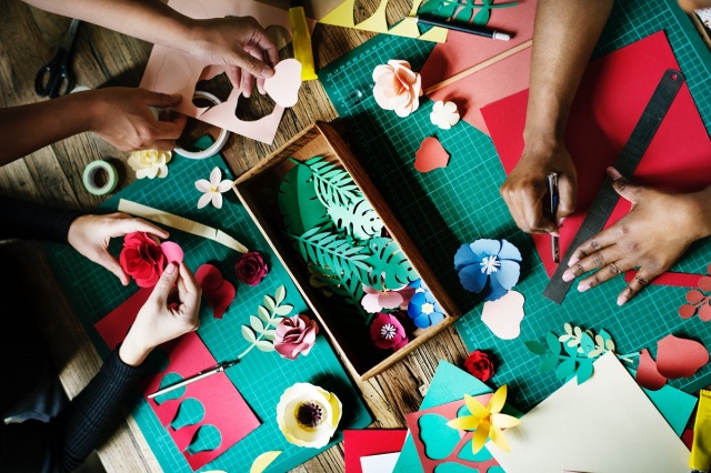 Three sets of hands making paper crafts