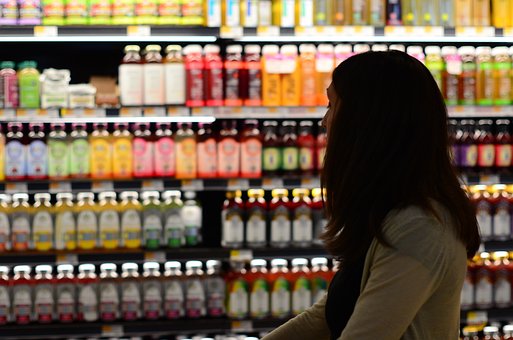 person with long hair, in grocery store, looking at drinks on shelf
