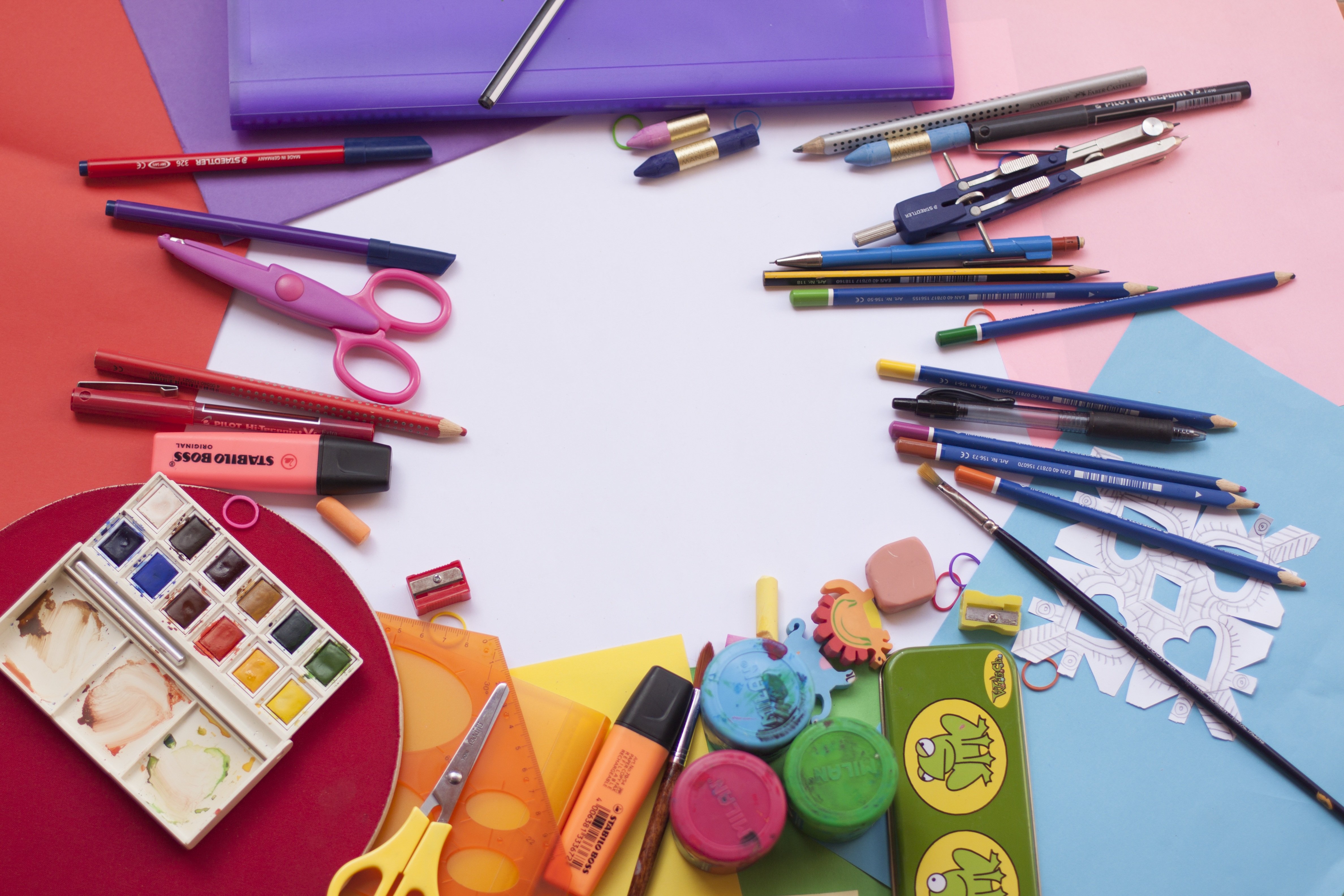 Various art supplies arranged in a circle on colorful paper.