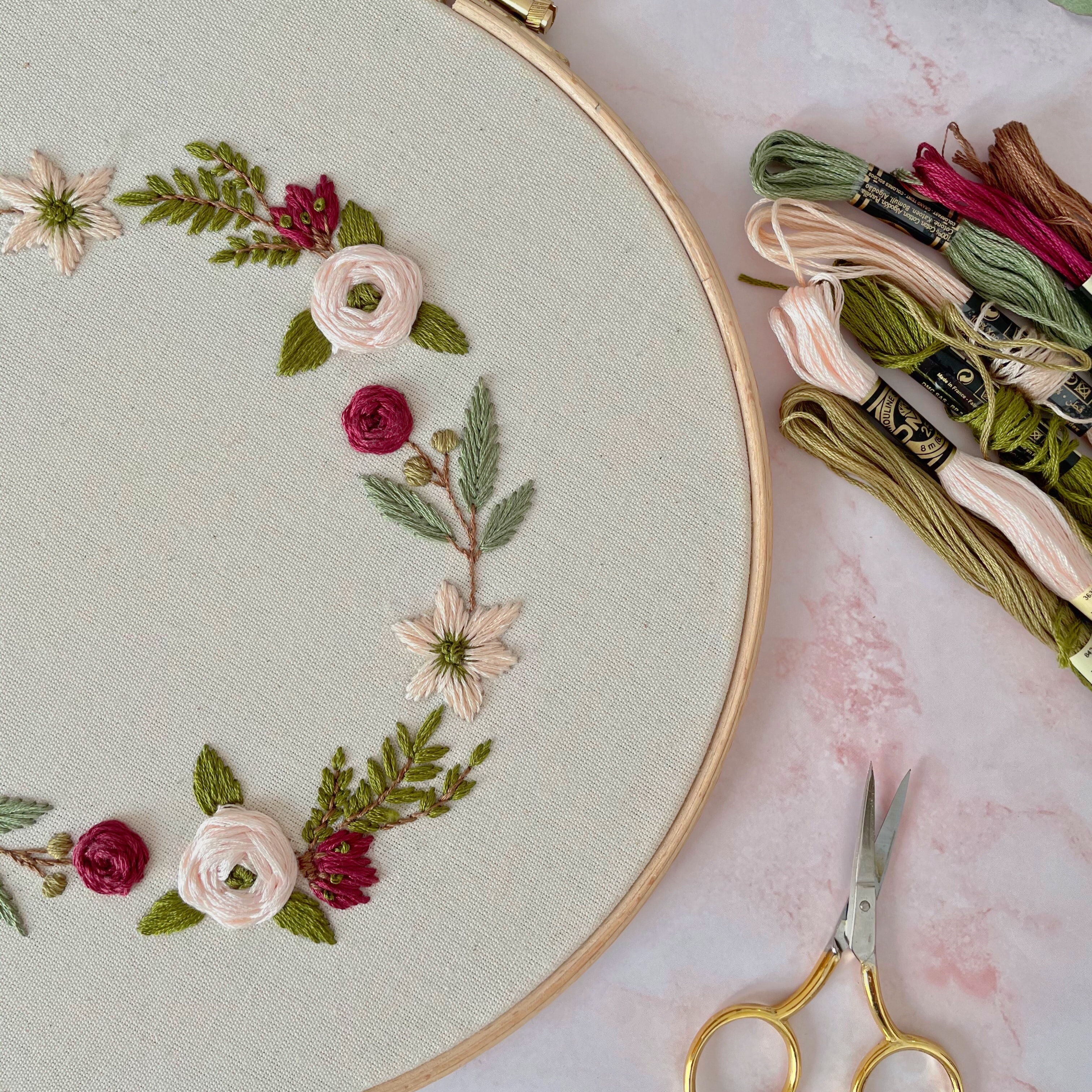 embroidered flowers with embroidery thread and scissors beside the hoop