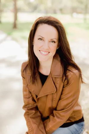 A headshot of author Sarah Penner, sitting outside in a brown jacket.
