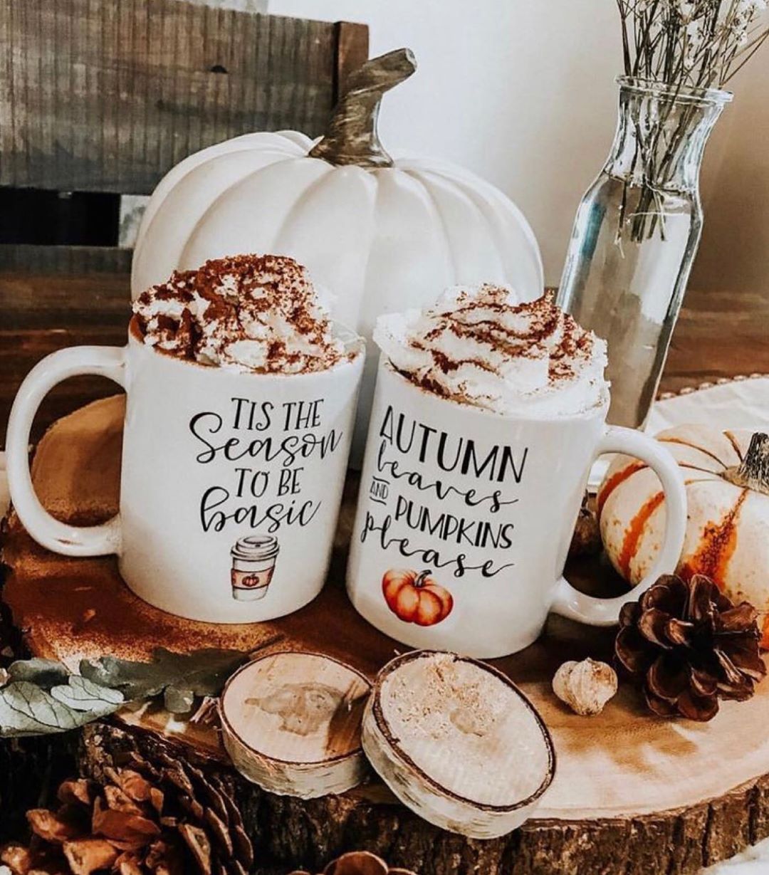 Fall themed mugs with whipped cream and a white pumpkin in the background.