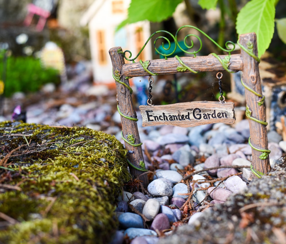 Miniature sign that reads "Enchanted Garden" over a pebble path.