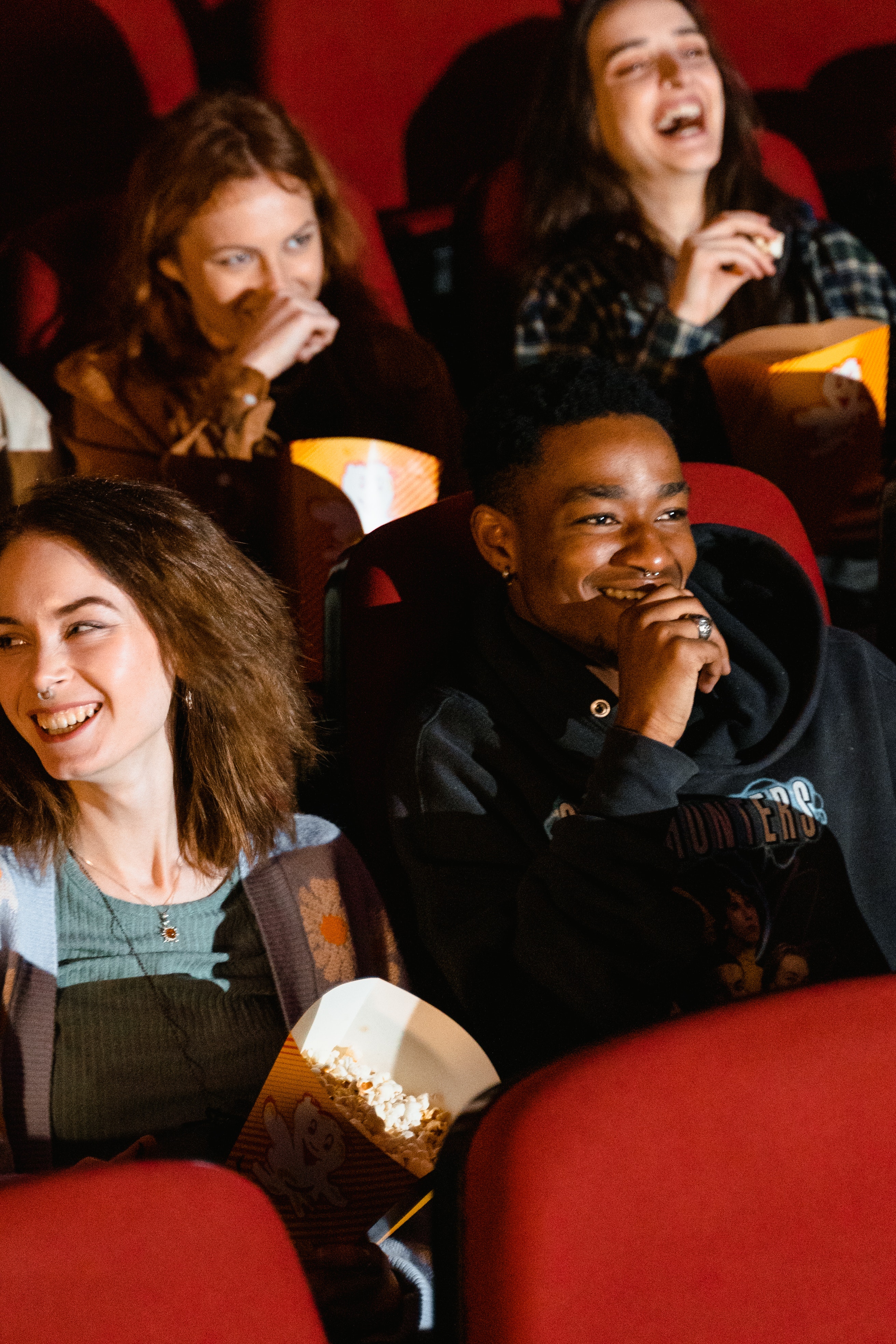Teens in movie theatre laughing at a movie