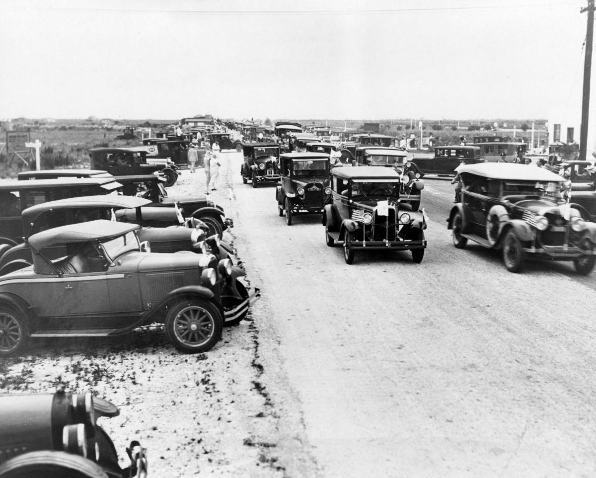 Black and white photograph of cars traveling down a dirt road Tamiami Trail.