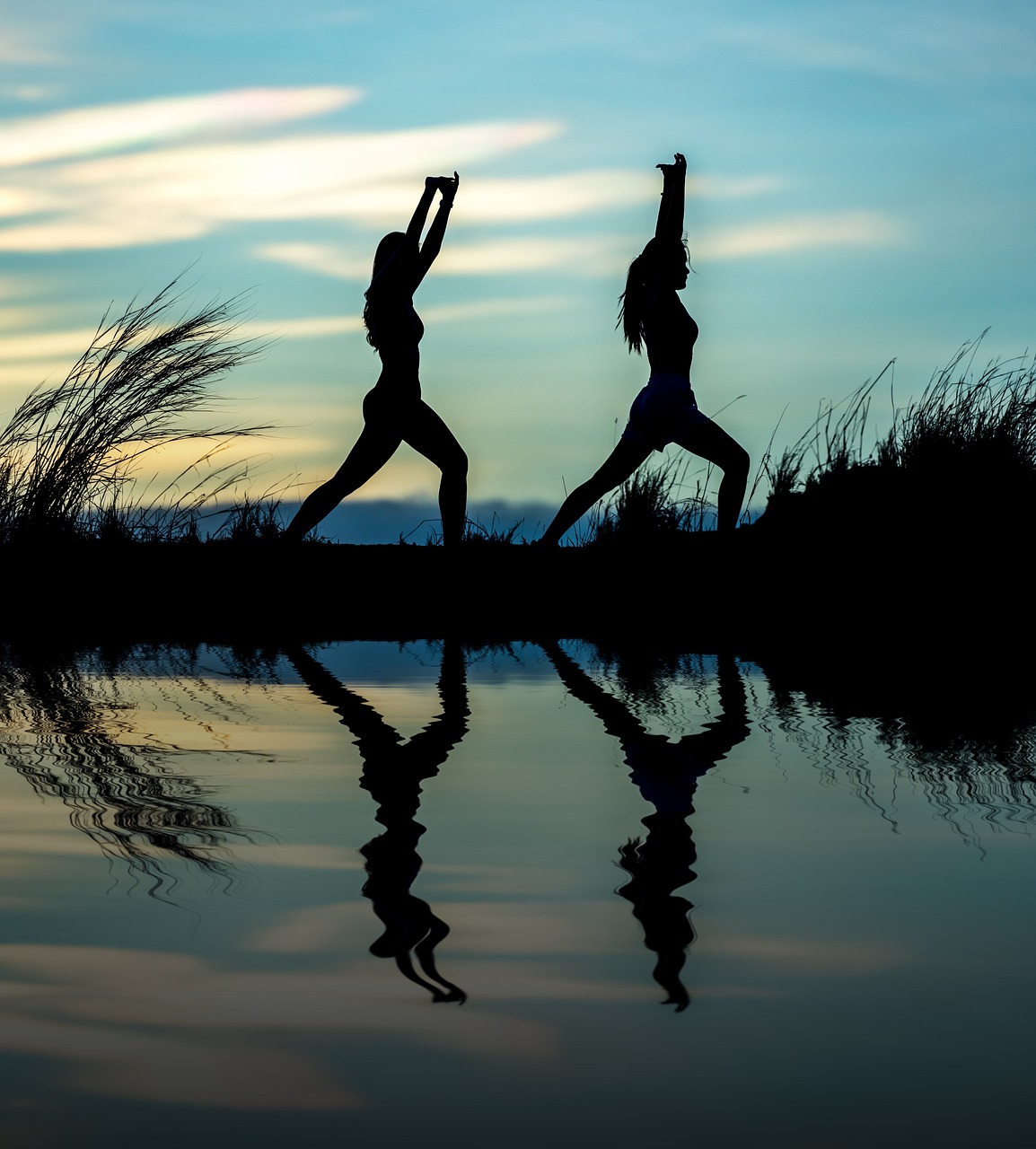 Two silhouettes of women doing yoga.
