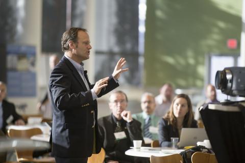 Man wearing a suit speaking to a group of people