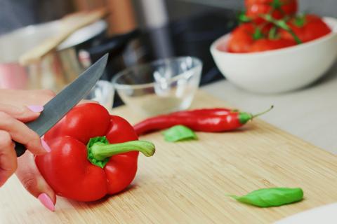 Person cutting a bell pepper on a cutting board.