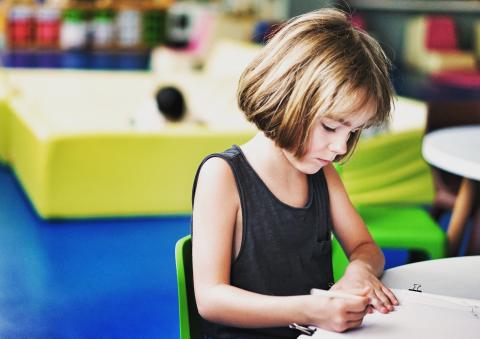 Girl sitting at a table working on something.