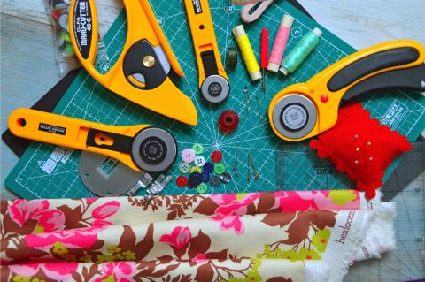 Table with sewing tools, pins, thread and fabric