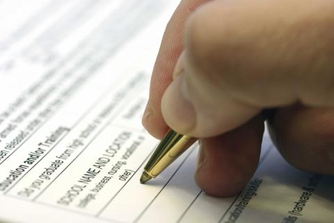 hand with pen writing on job application