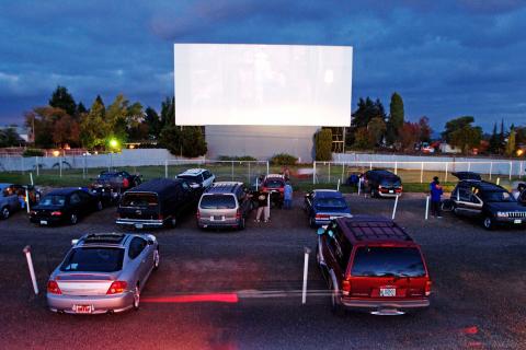 Large outdoor movie screen with cars parked facing it.