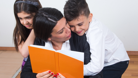 a family of 3 reading a book together