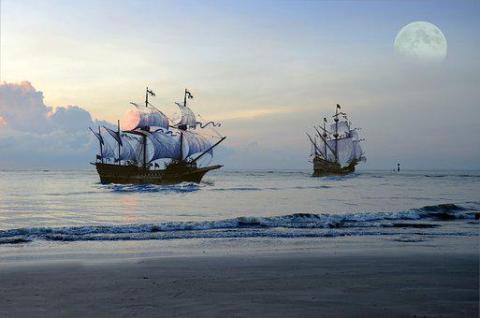 Two ships on the ocean, seen from shore.