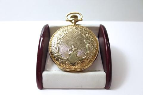 An old pocket watch sitting on a display stand.