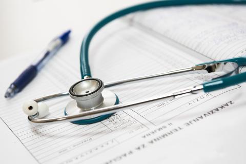 A stethoscope on a pad of paper along with a pen.