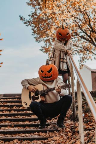 Two figures posing wearing wearing pumpkin head masks