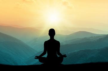 Meditating with sunrise and mountains in the background