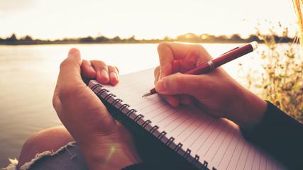 writing in a notebook by a lake.