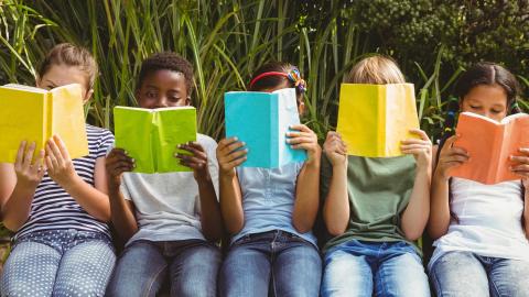 Children sitting in a row reading books.