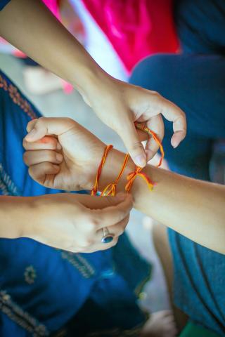 person tying friendship bracelet onto another person's wrist