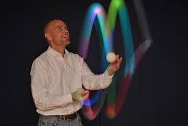 Man juggling glow-in-the-dark balls.
