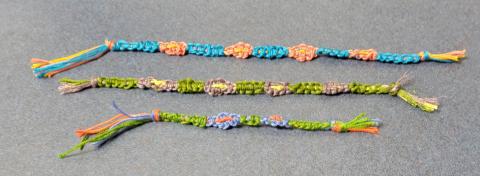 Three braided bracelets made with different colors of thread.
