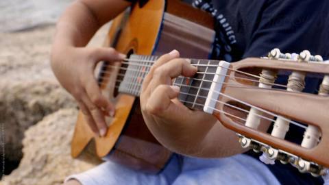 Young hands playing an acoustic guitar.