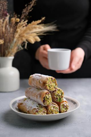 Figure holding a cup of coffee and a plate of cannoli