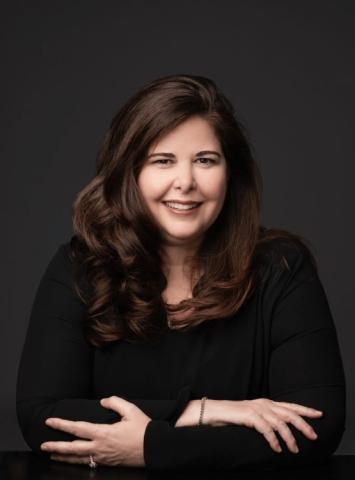 Author Lisa Unger wearing a black shirt in front of a gray background.