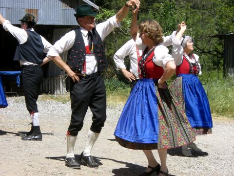 Four German folk dancers dressed in traditional clothing.