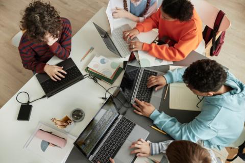 Overhead view of teens using laptops.