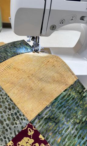 Fabric squares been sewn together on a sewing machine.