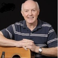 Photo of Dave Moran holding an acoustic guitar.